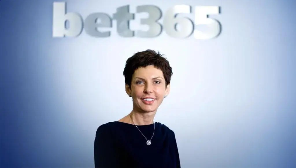 Denise Coates, founder and CEO of Bet365, standing in front of the company logo.